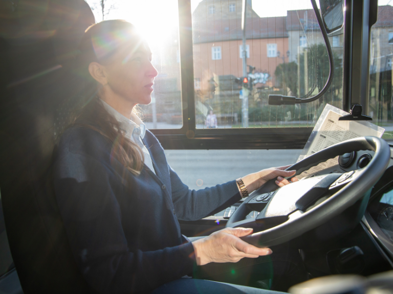 Une chauffeuse d'autobus en prise en photo de profil, alors qu'elle conduit au volant de son véhicule.